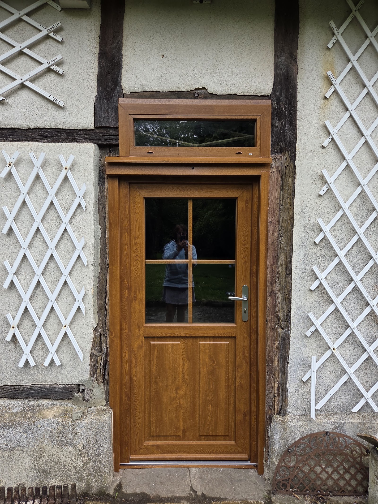Pose d'une porte d'entrée en PVC imitation bois sur une façade à colombages
